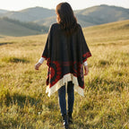 Cape poncho femme ouverte à motif et franges, portée de dos par une femme marchant dans un champ