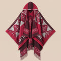 Cape poncho femme ouverte rouge à franges, présentée à plat de face sur fond crème, capuche et motifs géométriques visibles
