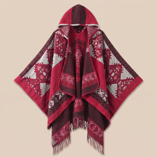 Cape poncho femme ouverte rouge à franges, présentée à plat de face sur fond crème, capuche et motifs géométriques visibles