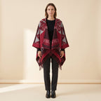 Cape poncho femme ouverte rouge à franges portée de face, ouverte sur un haut noir, capuche rabattue dans le dos
