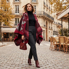 Cape poncho femme ouverte rouge à franges portée de face par une femme en ville, dévoilant son tombé fluide et ses motifs