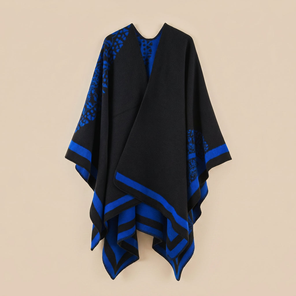 Manteau poncho femme, cape ouverte à bordure noire et bleue, avec motifs bleus, posé à plat sur fond clair