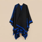 Manteau poncho femme, cape ouverte à bordure noire et bleue, avec motifs bleus, posé à plat sur fond clair