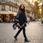Manteau poncho femme, cape ouverte à bordure noire et grise, avec motifs, portée par une femme marchant en extérieur