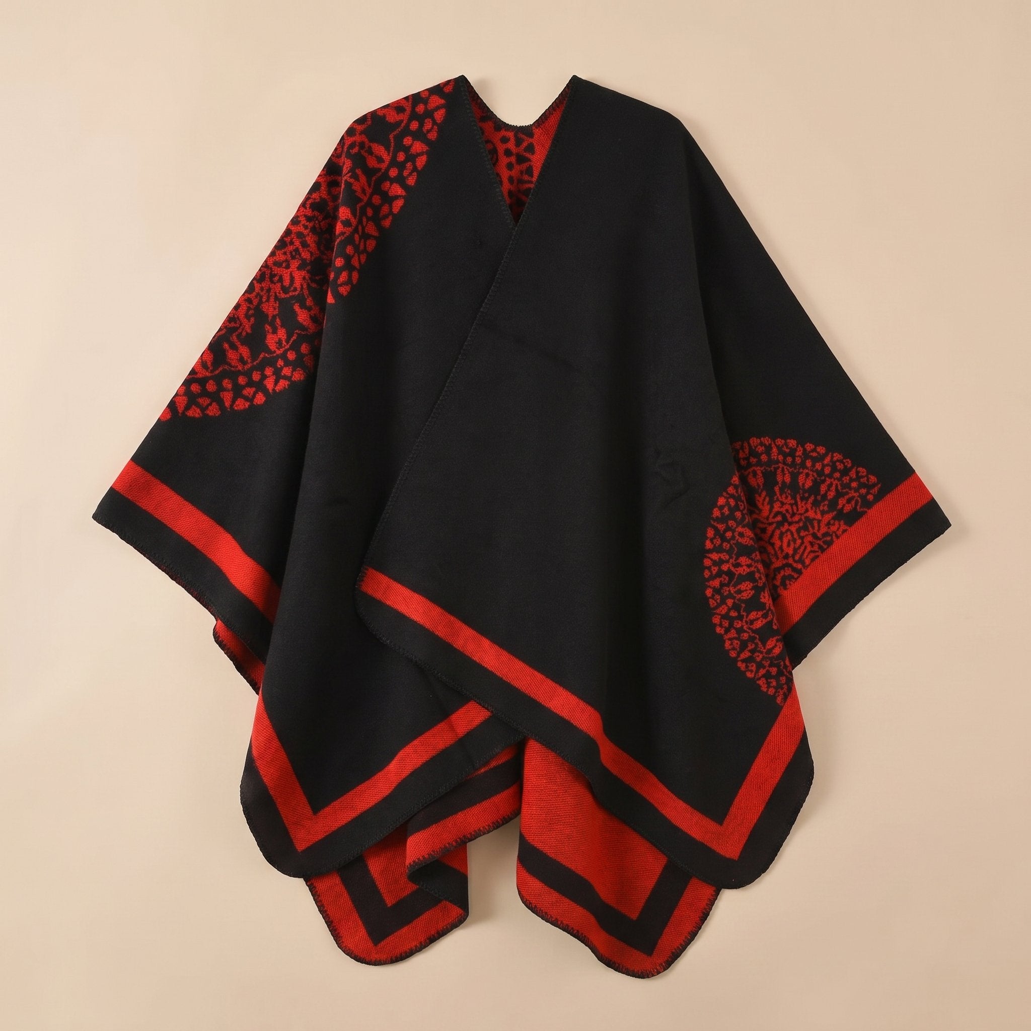 Manteau poncho femme, cape ouverte à bordure noire et rouge, avec motifs circulaires et géométriques, posé à plat