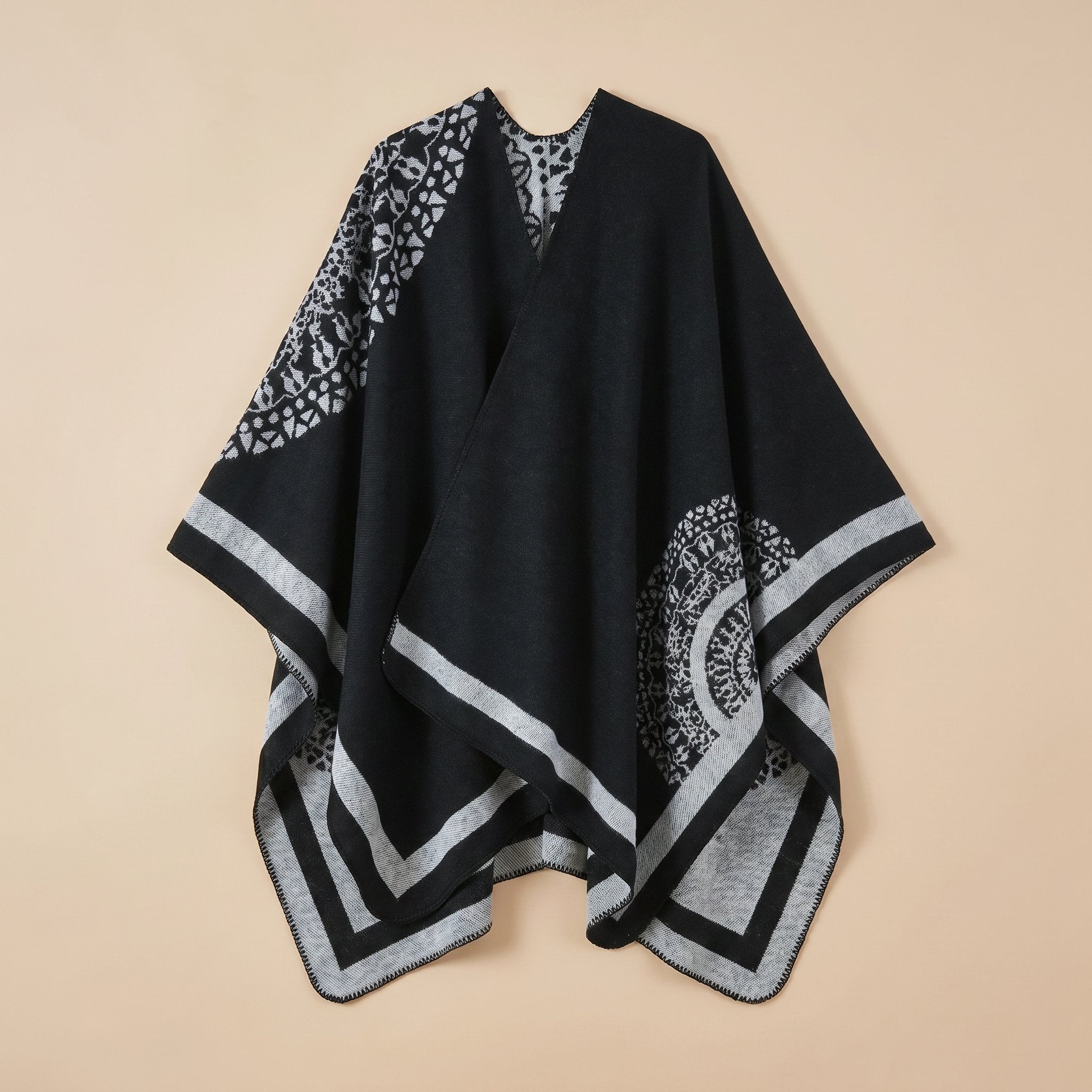 Manteau poncho femme, cape ouverte à bordure noire et grise, avec motifs géométriques et circulaires, posé à plat