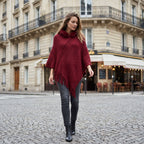 Poncho à capuche femme en maille à franges, coloris bordeaux, porté par une femme marchant en ville