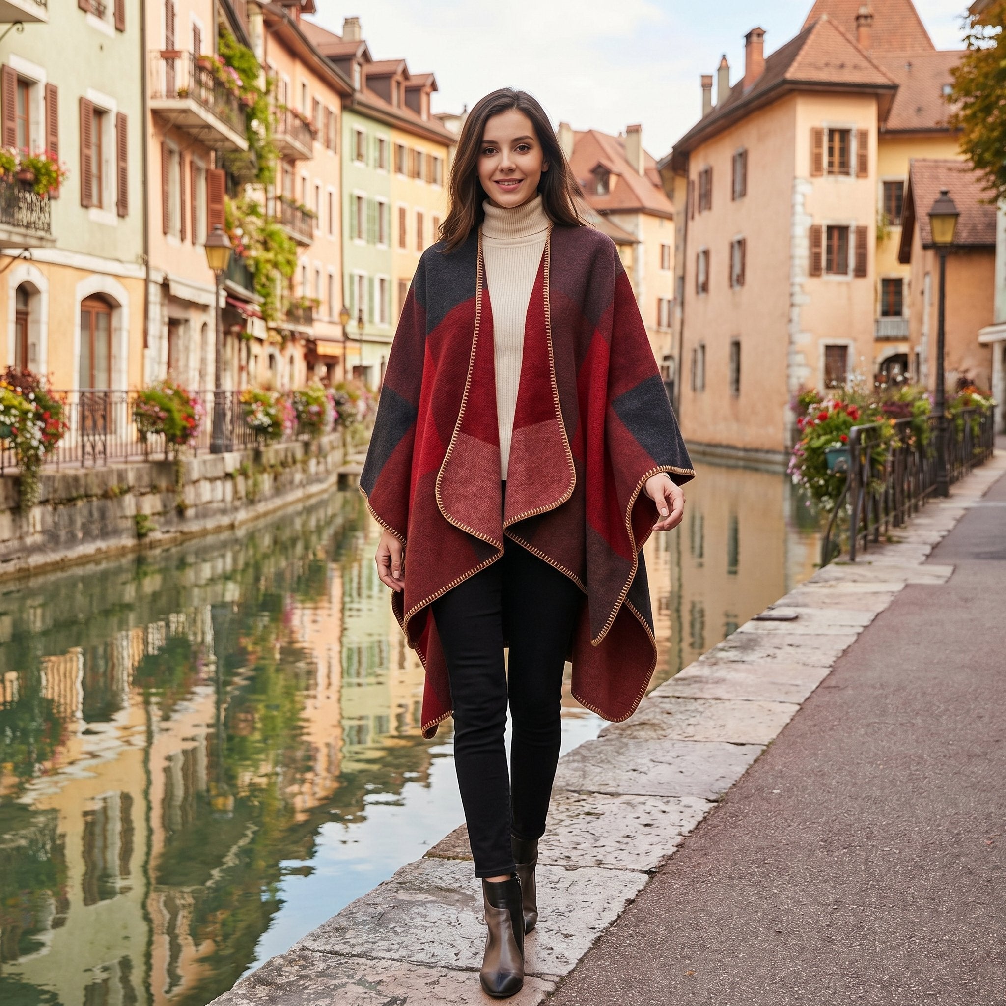 Poncho cape colorblock rouge, porté par une femme souriante marchant le long d'un canal.