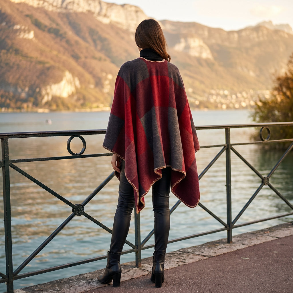 Poncho cape colorblock rouge, porté par une femme vue de dos contemplant un lac et des montagnes.