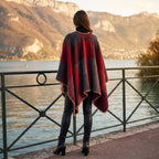 Poncho cape colorblock rouge, porté par une femme vue de dos contemplant un lac et des montagnes.
