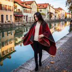 Poncho cape colorblock rouge, porté par une femme marchant sur un quai au bord d'un canal.