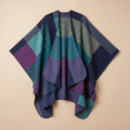 Poncho cape colorblock vert et violet posé à plat, montrant ses motifs géométriques.