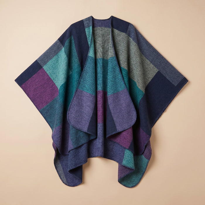 Poncho cape colorblock vert et violet posé à plat, montrant ses motifs géométriques.