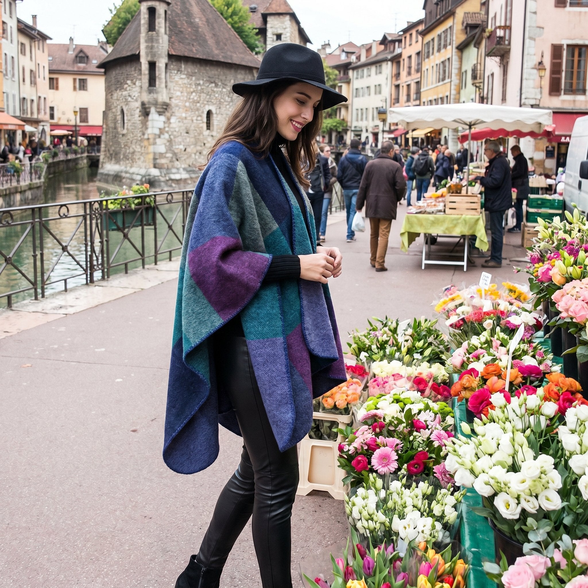Poncho cape colorblock vert et violet porté par une femme avec un chapeau, regardant des fleurs au marché.