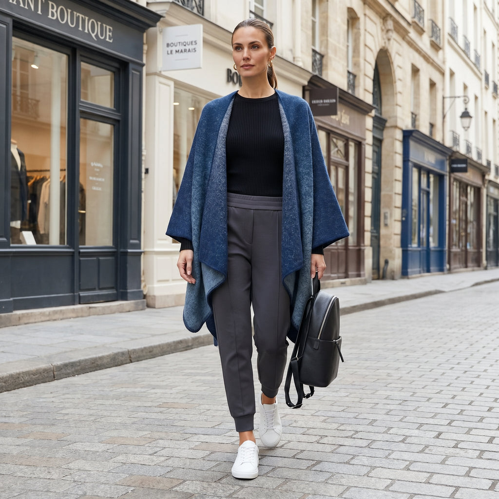 Poncho cape femme bleu jean porté par une femme marchant dans une rue commerçante, vue de face.