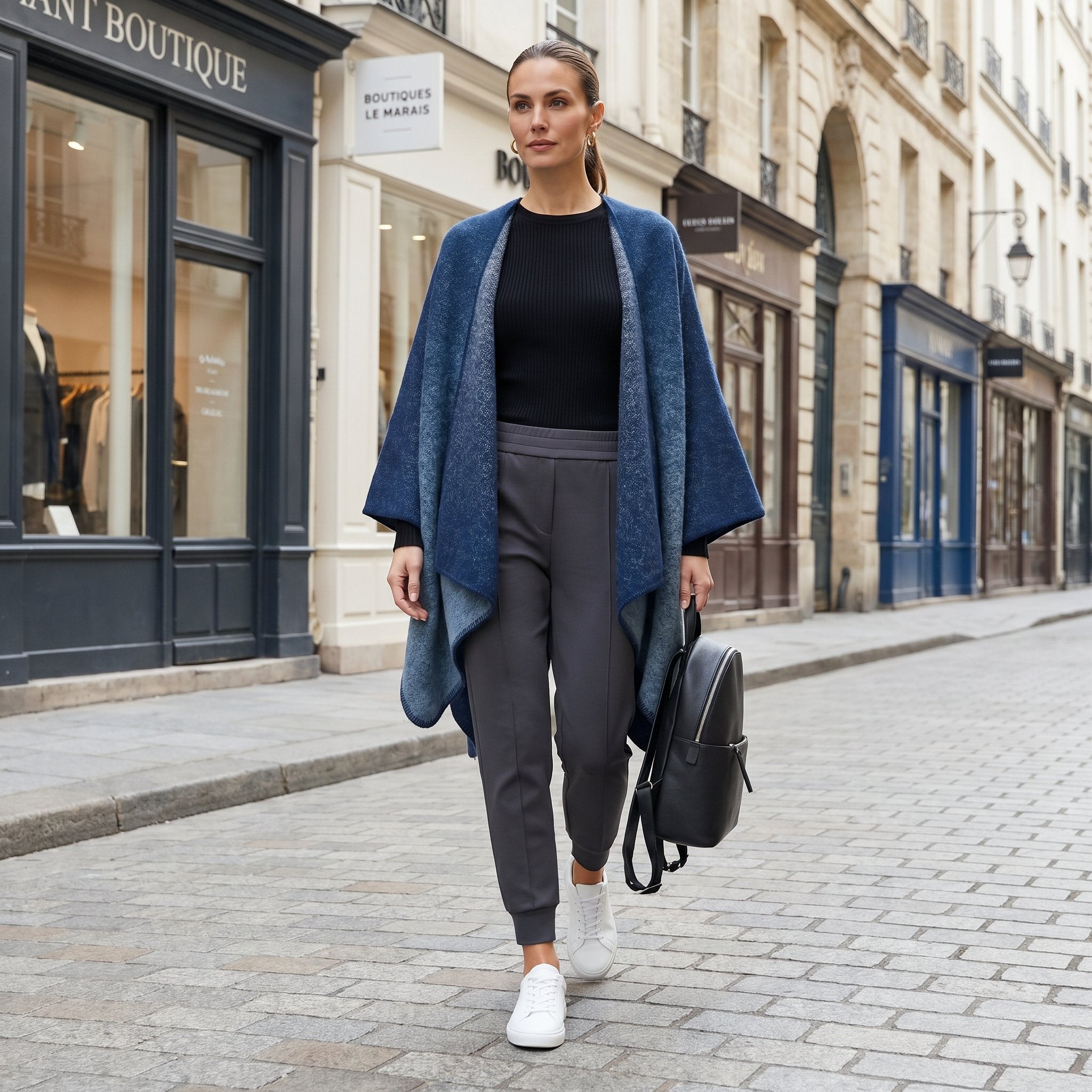 Poncho cape femme bleu jean porté par une femme marchant dans une rue commerçante, vue de face.
