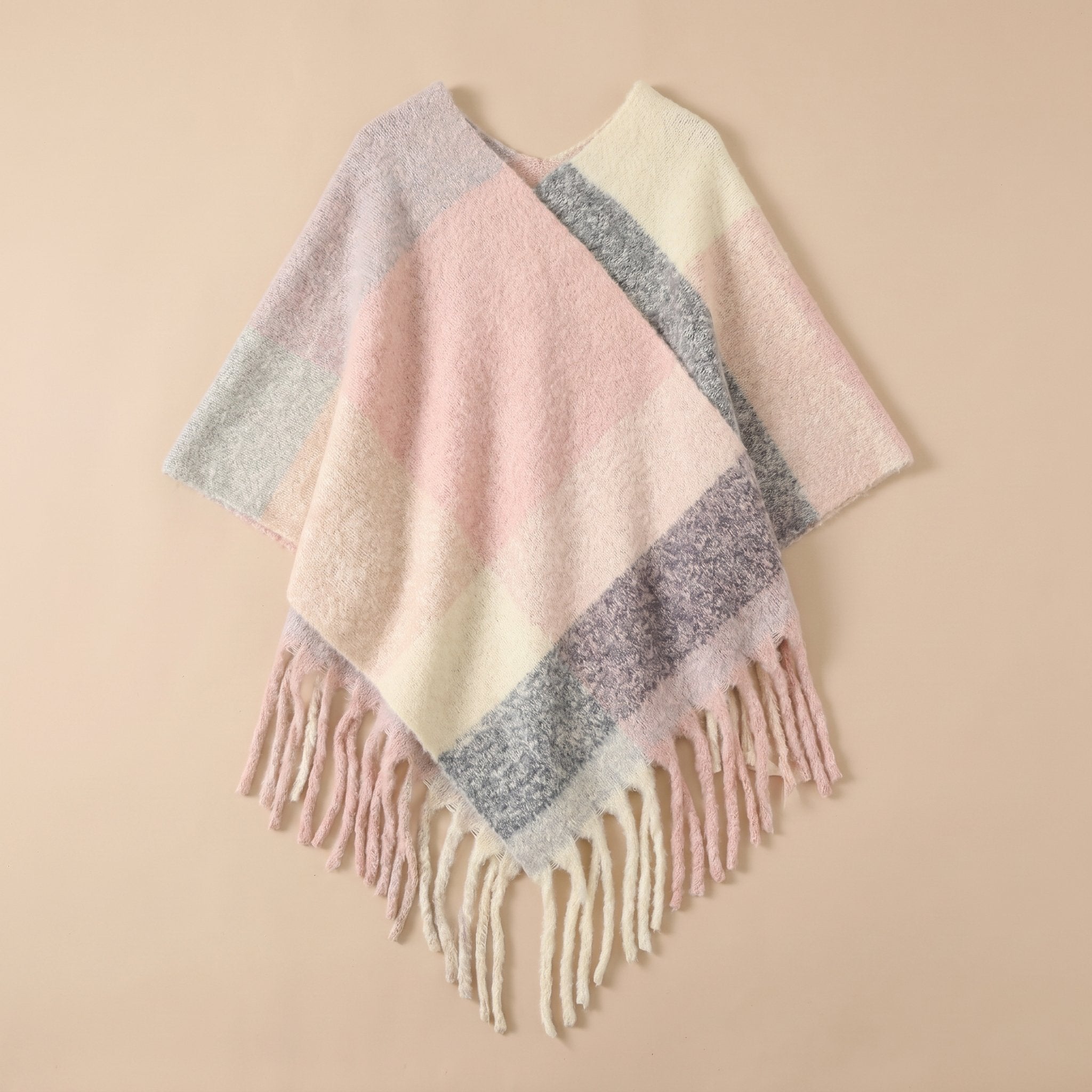 Poncho cape femme colorblock pastel posé à plat, montrant les nuances douces et les franges.