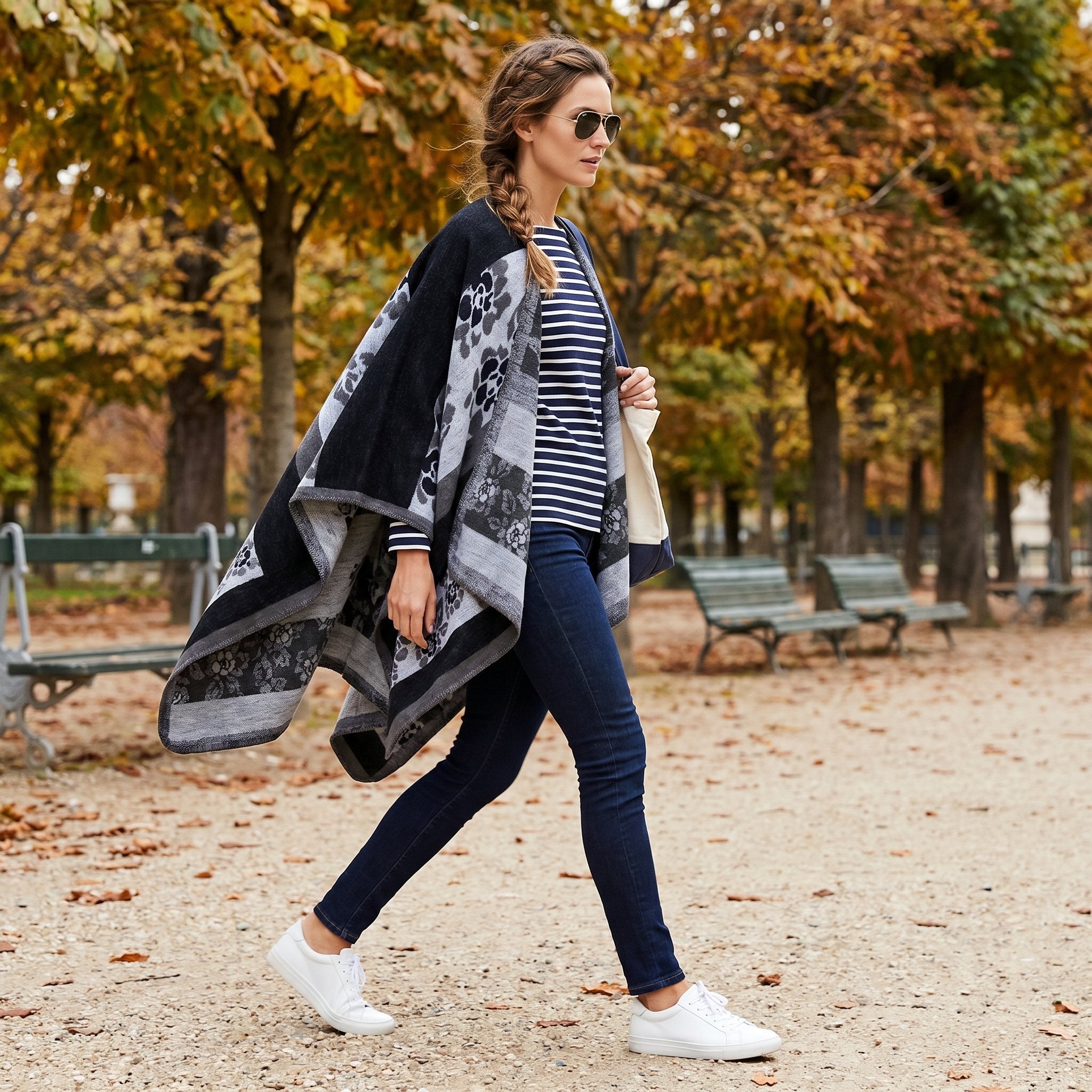 Poncho cape femme motif floral noir et gris, porté par une femme marchant de profil dans un parc.