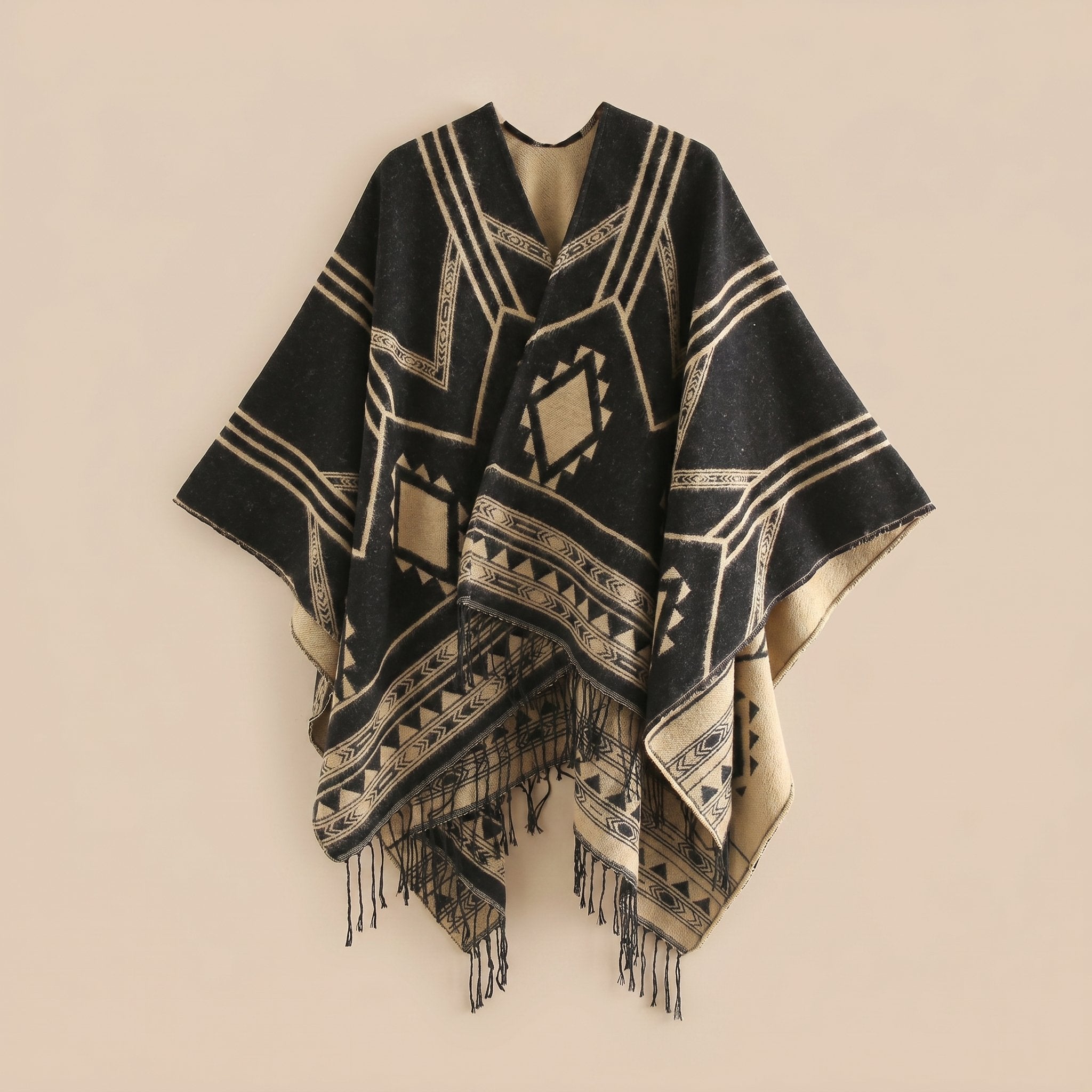 Poncho cape femme à motif géométrique et franges noir et beige, présenté à plat, montrant les motifs et les franges