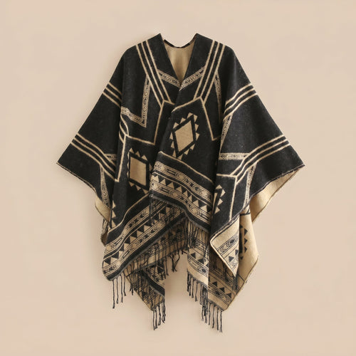 Poncho cape femme à motif géométrique et franges noir et beige, présenté à plat, montrant les motifs et les franges