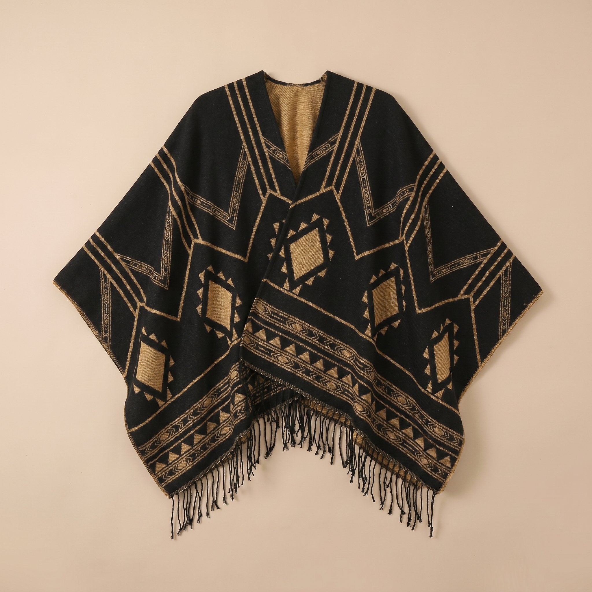 Poncho cape femme à motif géométrique et franges noir et marron clair, présenté à plat sur un fond uni, vue de face