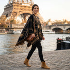 Poncho cape femme à motif géométrique et franges noir et marron clair, porté par une femme marchant en extérieur, de profil
