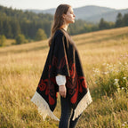 Poncho cape femme ouvert noir et rouge, porté de côté par une femme, détaillant la coupe ample et les longues franges crème