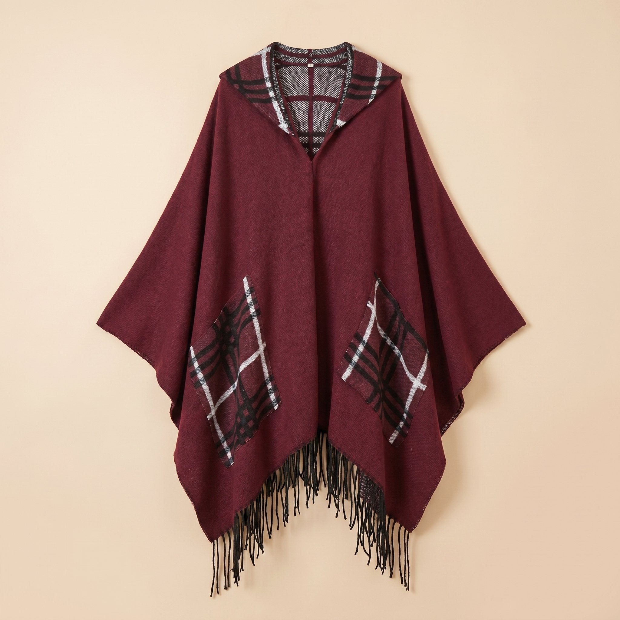 Poncho cape homme à carreaux avec poches bordeaux, présenté à plat de face, avec ses motifs à carreaux et franges visibles