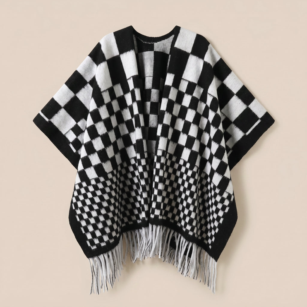 Poncho cape homme à damier noir et blanc, posé à plat de face, montrant les franges blanches