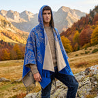 Poncho cape homme à franges bleu et beige, porté par un homme avec capuche sur la tête en extérieur