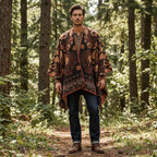 Poncho cape homme motif Paisley cuivre, porté par un homme debout de face dans un sous-bois verdoyant.