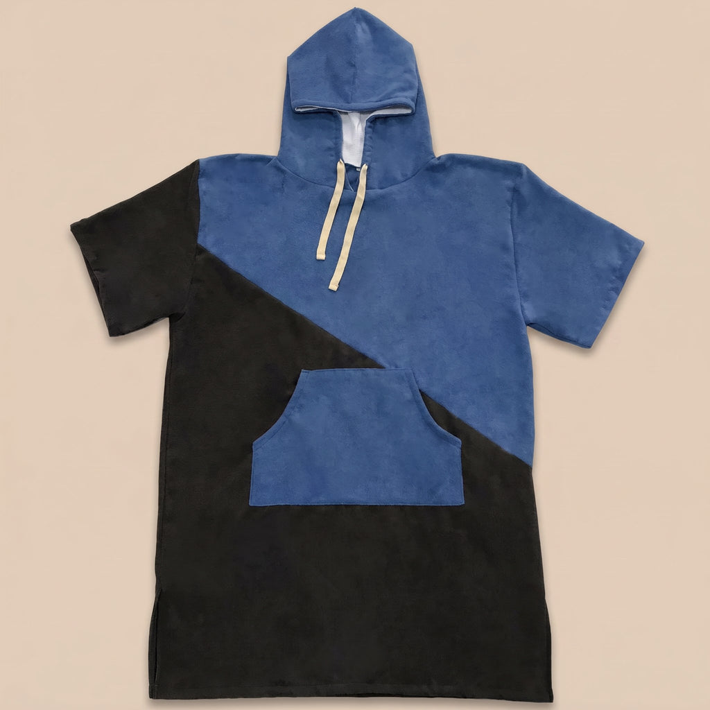 Poncho serviette à capuche bicolore bleu et noir, posé à plat sur un fond uni.