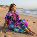 Poncho serviette a capuche motif girafe mandala, porté par une femme assise de profil sur le sable de la plage.