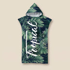Poncho serviette à capuche motif feuillage tropical, présenté à plat sur un fond beige uni.