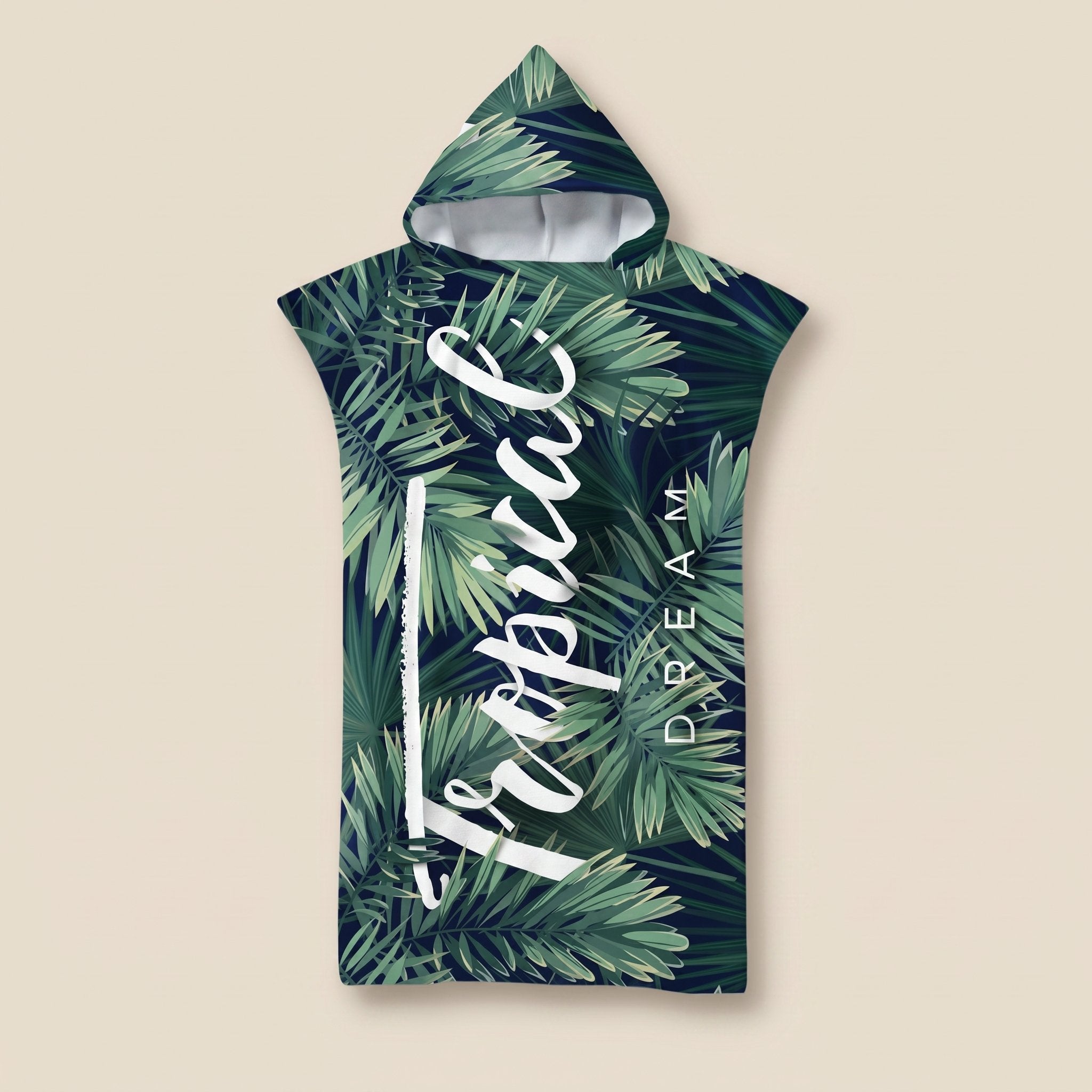 Poncho serviette à capuche motif feuillage tropical, présenté à plat sur un fond beige uni.