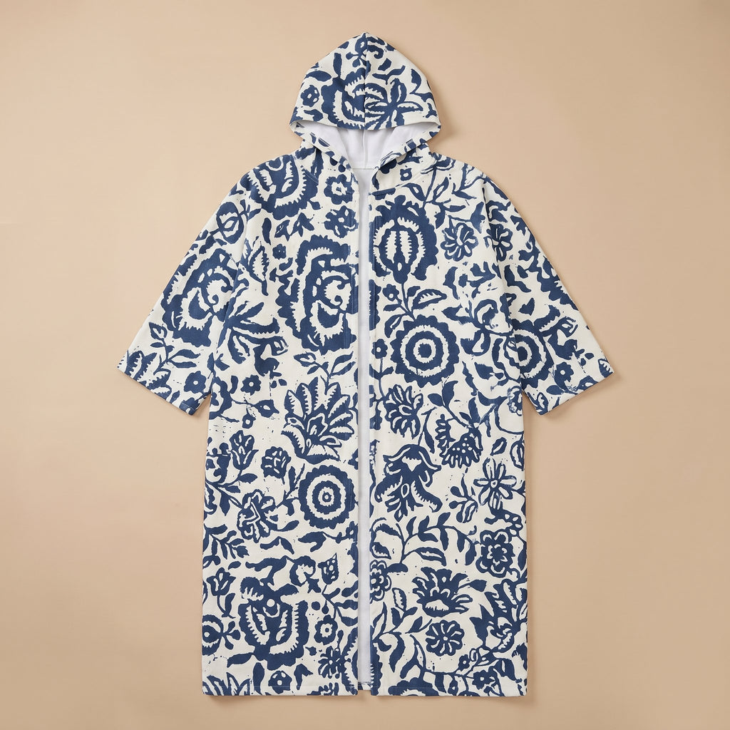Poncho serviette à capuche motif fleurs bleues, présenté à plat sur un fond uni.