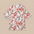 Poncho serviette a capuche motif paisley colore, presente a plat sur fond uni beige.