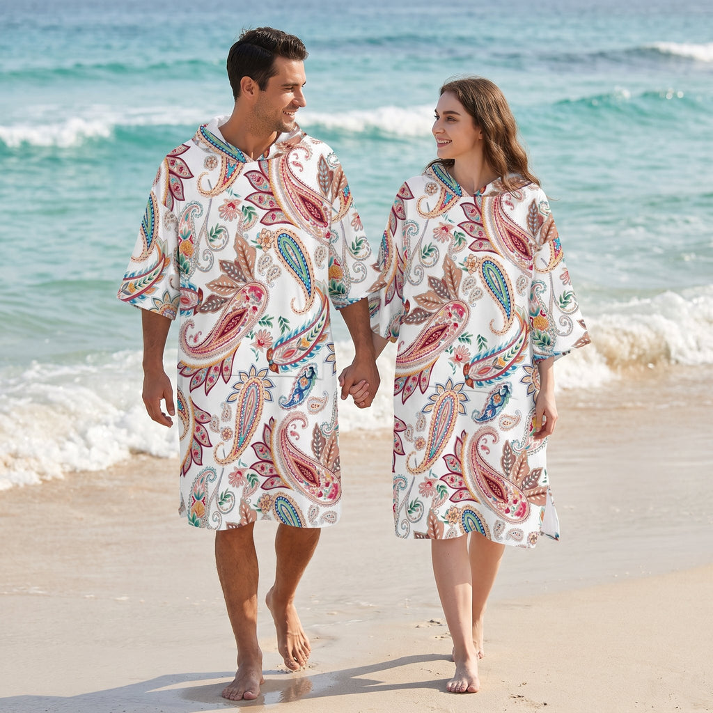 Poncho serviette a capuche motif paisley colore, porte par un couple marchant sur la plage.