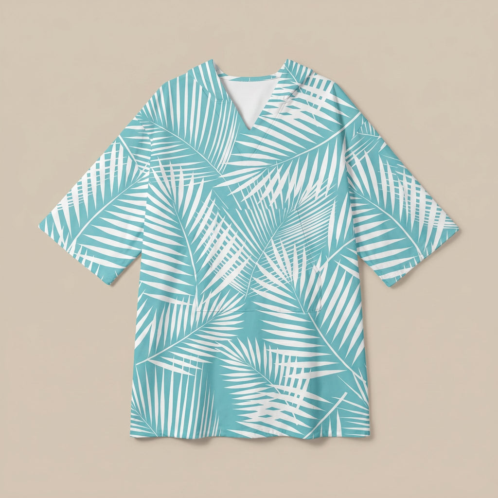 Poncho serviette à capuche motif palmes turquoise, posé à plat sur un fond uni beige.