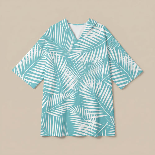Poncho serviette à capuche motif palmes turquoise, posé à plat sur un fond uni beige.
