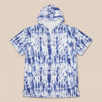 Poncho serviette a capuche motif tie-dye bleu, présenté à plat sur un fond uni clair.