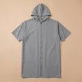 Poncho de bain zippé gris uni posé à plat sur un fond beige clair, montrant la fermeture éclair centrale.