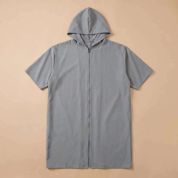 Poncho de bain zippé gris uni posé à plat sur un fond beige clair, montrant la fermeture éclair centrale.
