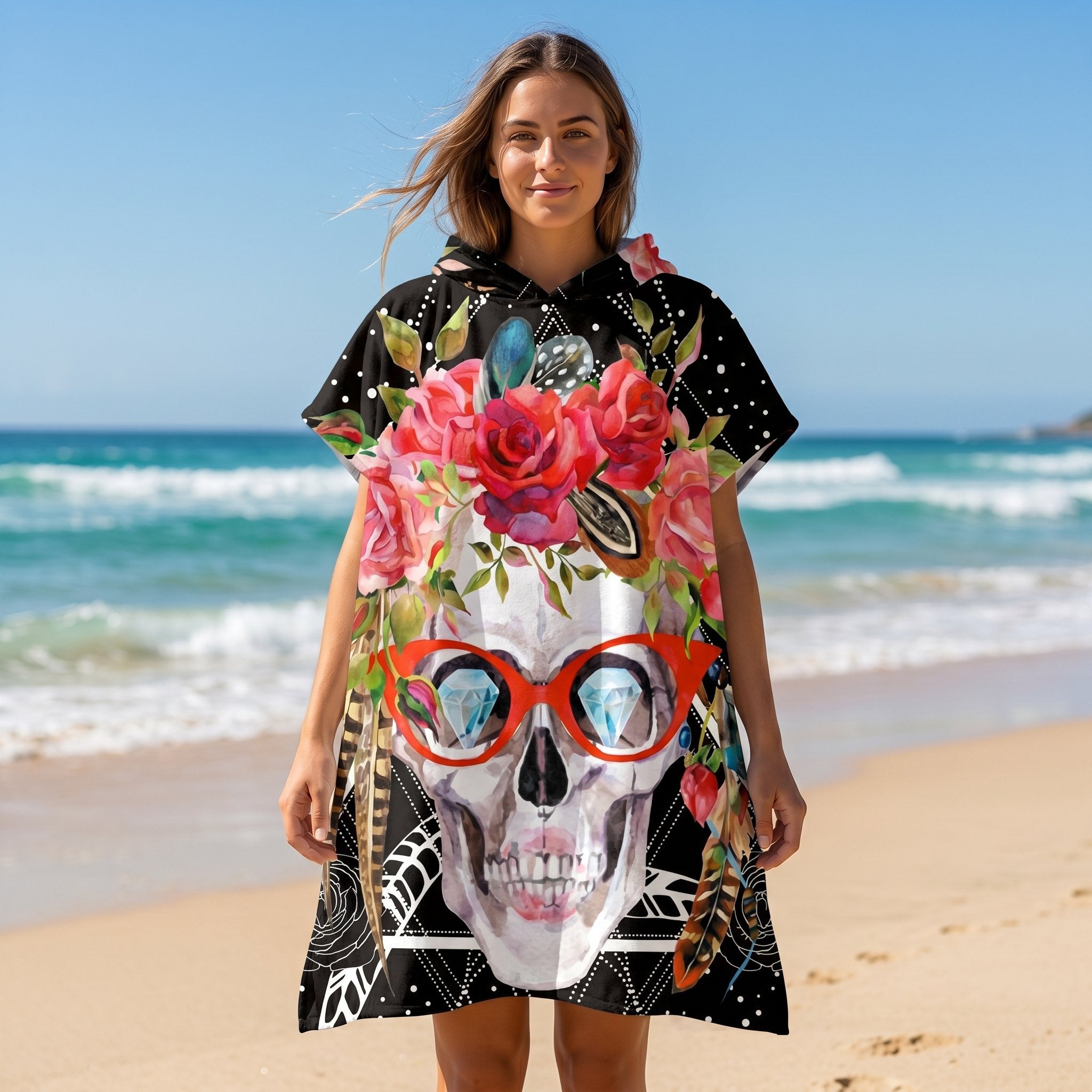 Poncho serviette à capuche motif crâne à lunettes, porté par une femme souriante sur la plage.
