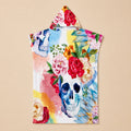Poncho serviette à capuche motif crâne fleuri, présenté à plat sur un fond uni clair.