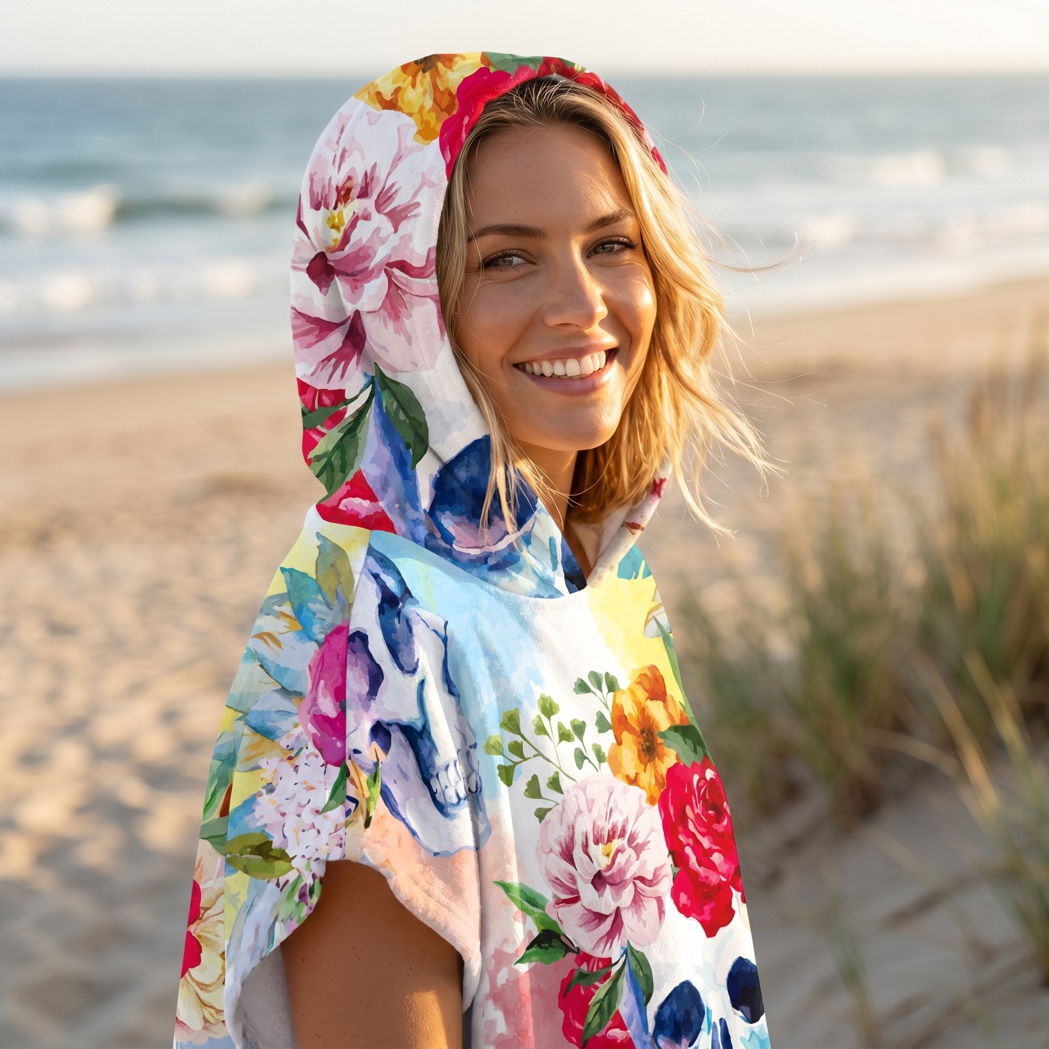 Poncho serviette à capuche motif crâne fleuri, porté par une femme souriante, la capuche relevée.