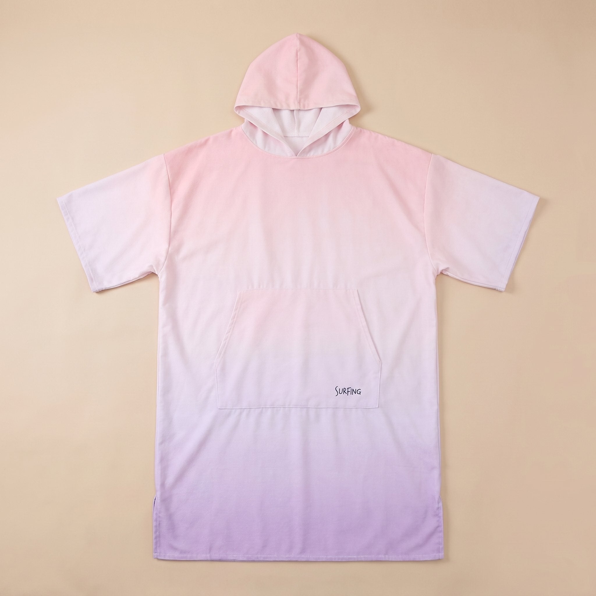Poncho serviette à capuche motif dégradé rose, présenté à plat sur un fond beige uni.