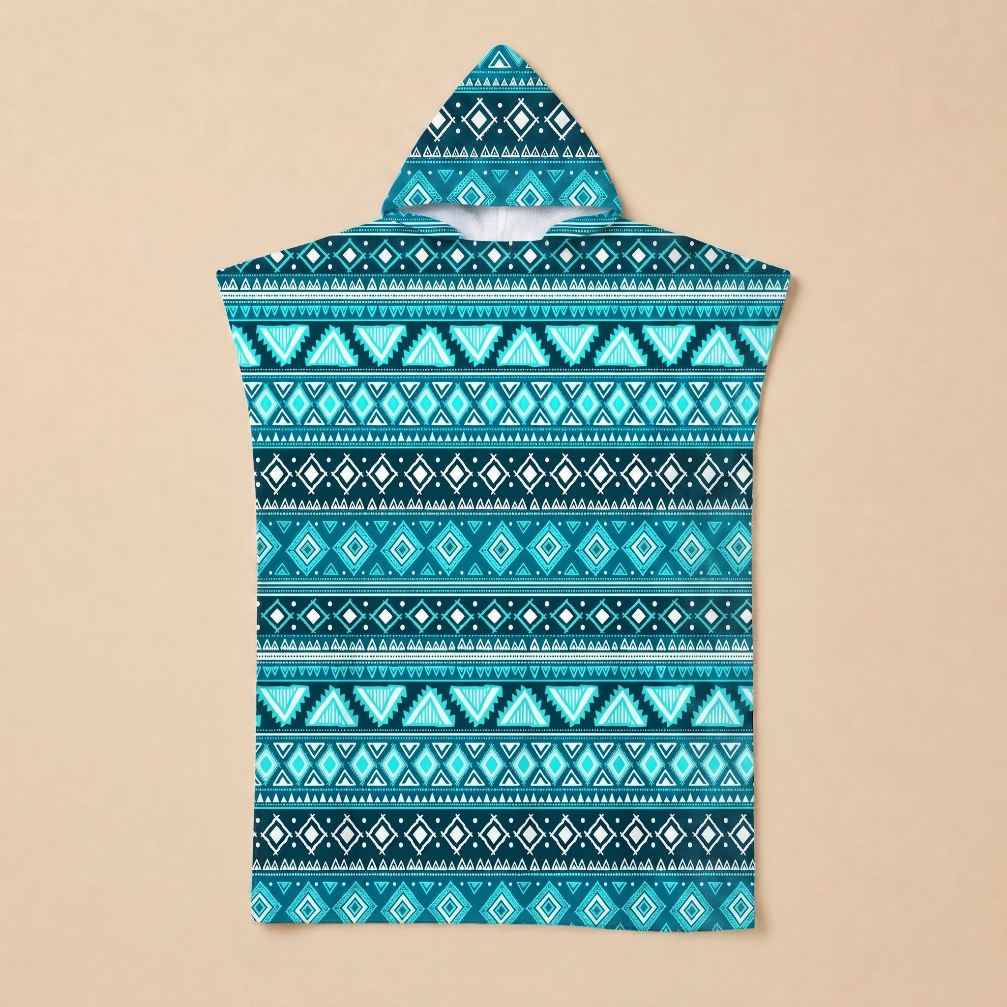 Poncho serviette à capuche motif aztèque bleu posé à plat sur un fond beige uni.