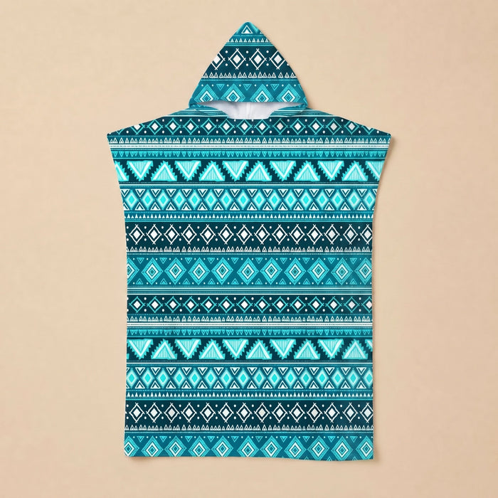 Poncho serviette à capuche motif aztèque bleu posé à plat sur un fond beige uni.