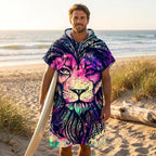 Poncho serviette à capuche motif lion psychédélique, porté par un homme tenant une planche de surf.